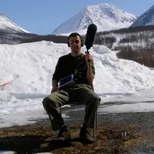 Photo de l'artiste Biosphere (aka Geir Jenssen) en train d'enregistrer au milieu des montagnes enneigées.