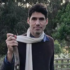 Photo de l'artiste DAVID SHEA avec une écharpe blanche et un bâton dans un parc