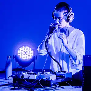 Photo en bleu et blanc de l'artiste DULLMEA devant un micro et une table de mixage