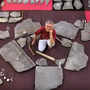 Photo de l'artiste Emmanuel Dilhac au Au centre d'une installation géante, composée de pierres.