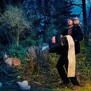 Photo de l'artiste KABOOM KARAVAN avec son instrument de musique et des animaux dans un bois