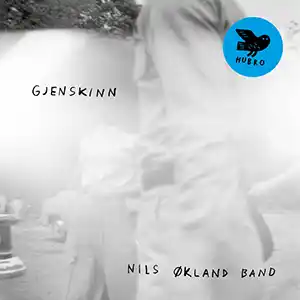 Pochette de l'album de NILS ØKLAND BAND "Gjenskinn" on distingue une silhouette en gros plan avec une rue derrière, en noir et blanc