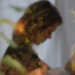 Artiste Catherine Graindorge tête penchée de profil devant un rideau en voile