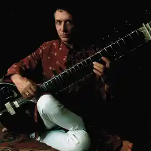 Photo de l'artiste Al Gromer Khan jouant du sitar en étant assis au sol.