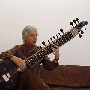 Photo de l'artiste Al Gromer Khan avec sa cithare indienne, un instrument à cordes de la famille des luths.