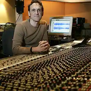 Photo du compositeur Alberto Iglesias dans son studio d'enregistrement assis devant une console de mixage
