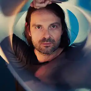 Photo de l'artiste ALESSANDRO CORTINI entouré d'un onde transparente