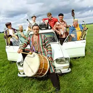 Photo du groupe Amsterdam Klezmer Band dans un champ autour d'une voiture
