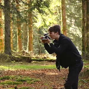 Photo de l'artiste BENOIT PIOULARD dans une forêt avec un polaroïd