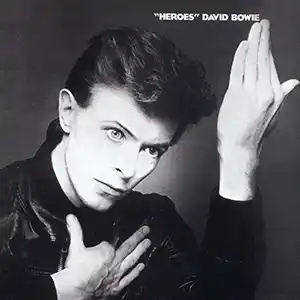 Pochette de l'album de DAVID BOWIE "Heroes", l'artiste en noir et blanc avec une main levée et l'autre autour de son col
