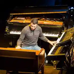 Photo de l'artiste Giogi Mikadze au milieu de ses instruments, des pianos