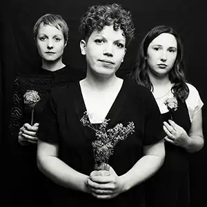 Photo du groupe Haiku Salut, un trio de trois musiciennes avec des fleurs à la main