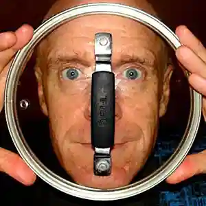 Photo de l'artiste Jim Coleman regardant derrière un couvercle de casserole en verre