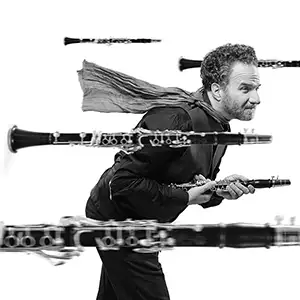 Photo de l'artiste David Krakauer au milieu de plusieurs clarinettes en plein vol