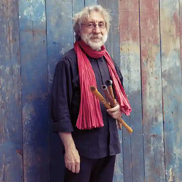 Photo de l'artiste Miqueù Montanaro avec une écharpe rouge et ses instruments, des galoubets provençaux