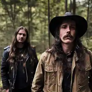 Photo des artistes Sean Kratz et du violoncelliste Kakaphonix du groupe néofolk Osi and the Jupiter. Photo prise en pleine nature dans une forêt.