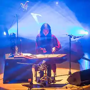 Photo de l'artiste Park Jiha sur scène avec son yanggeum, un instrument à cordes joué avec des tiges de bambou.