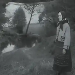 Photo d'une femme au bord d'un lac interprétant une chanson de guerre du sud de la Lituanie.