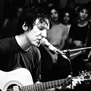 Photo de l'artiste Elliott Smith en concert avec sa guitare acoustique