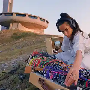 Photo de l'artiste Hélène Vogelsinger en train de composer au pied du monument de Bouzloudja ou maison du Parti communiste bulgare est une ancienne salle de congrès, aujourd'hui abandonnée, située en Bulgarie.